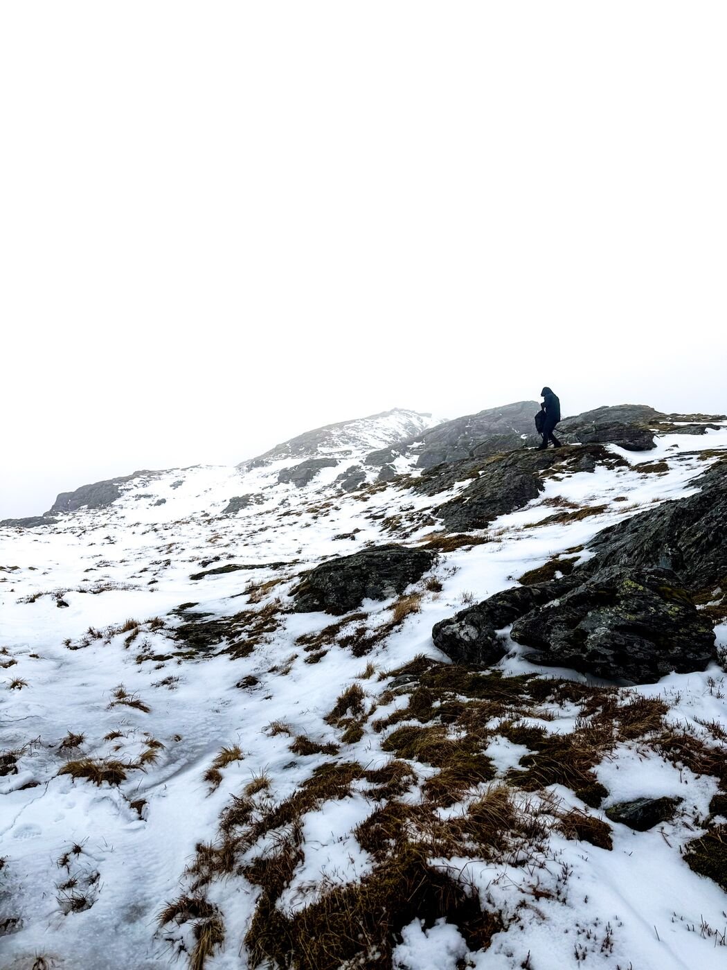 Hiker on a snowy Highland ridge under a bright sky