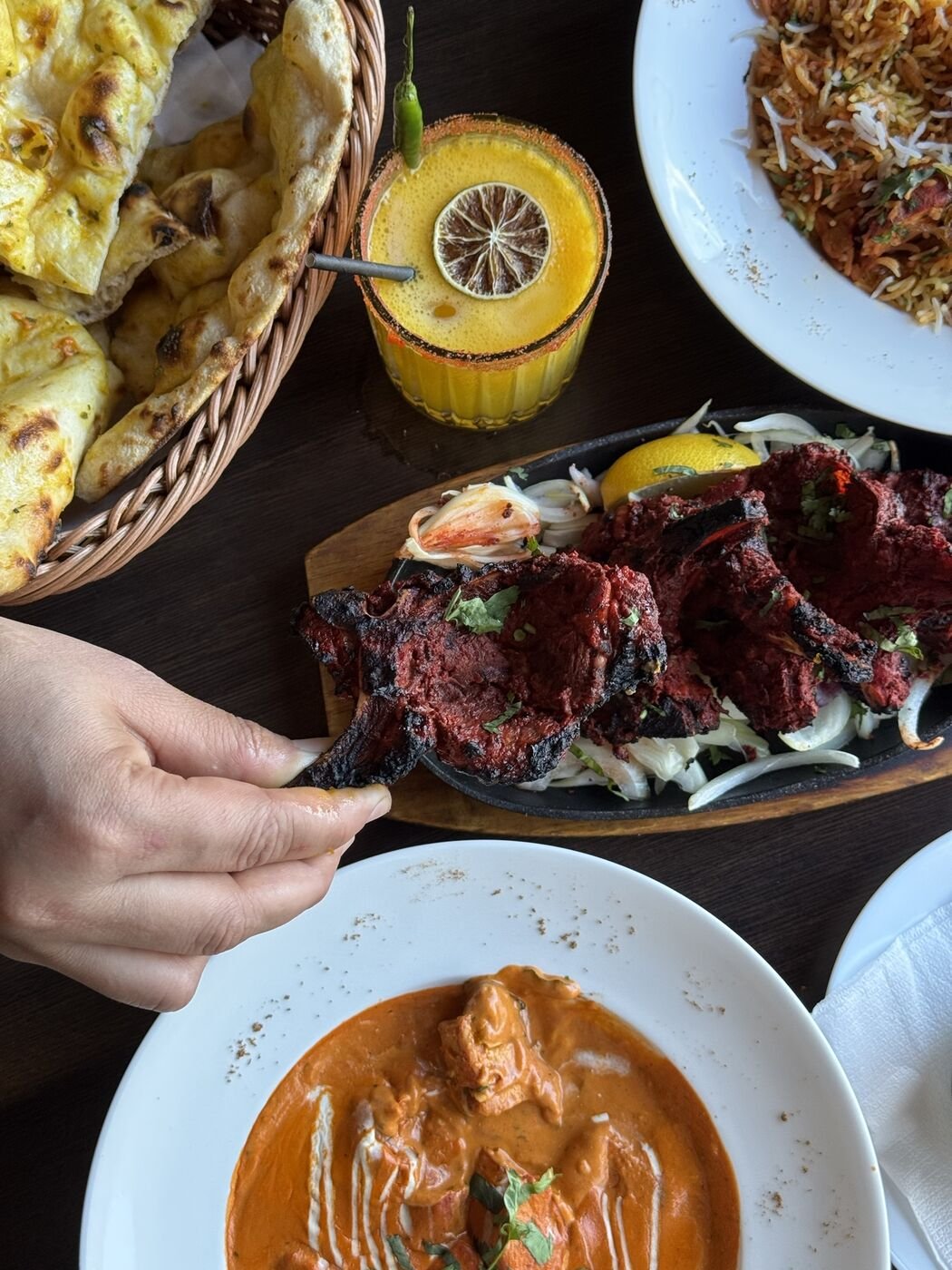 Tandoori lamb chops on a sizzler with a mango drink, restaurant food photography